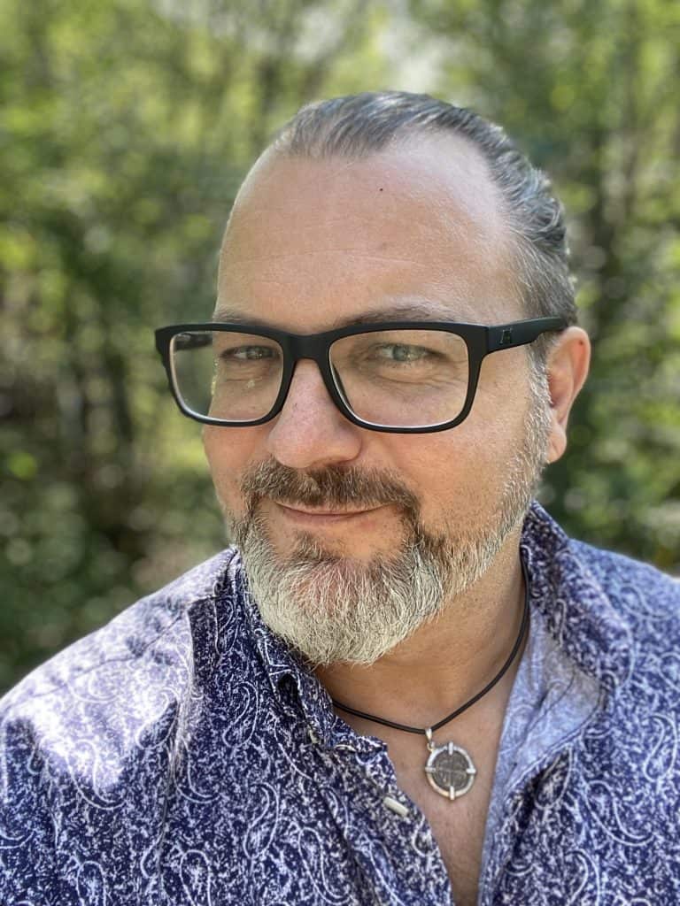 Close-up of a confident man outdoors wearing glasses, emphasizing innovative psychedelic-assisted recovery services for mental health support.